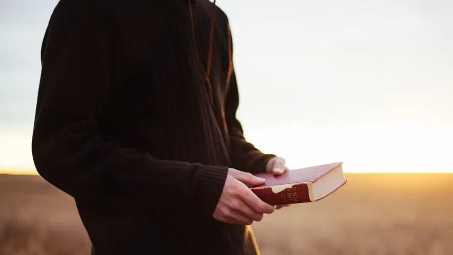 Man holding bible in a field